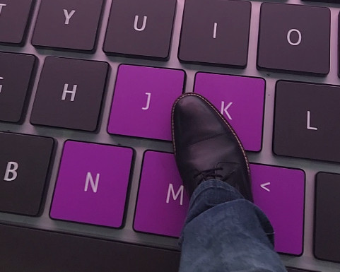 A foot stepping on some keys of the giant laptops keyboard 