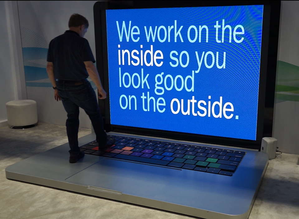 Man standing on top of the keyboard of a giant laptop